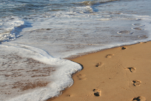 Footprints being washed away on the sandy beach.