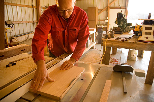 Man using table saw in home wood shop stock photo