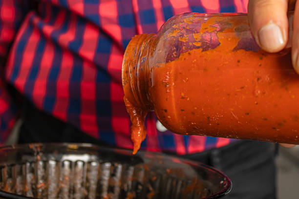 istock Man's hand putting tomato sauce for pizza and pasta. 1821468131