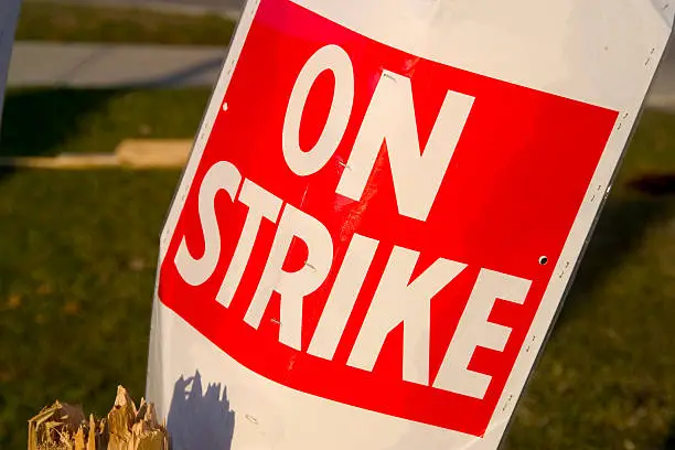 On Strike placard sits in garbage pail post strike. Narrow depth with soft background. Shot in sun setting light.