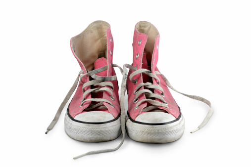 a pair of beat up pink baseball boots on a white background