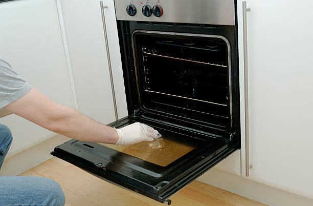 Man cleaning kitchen oven stove door stock photo