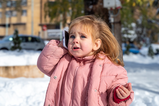 Experience the joy of winter through the eyes of a charming 1.5-year old baby girl, exploring the snowy wonderland in the park. Delight as she discovers the magic of the season, capturing precious moments with her mobile phone