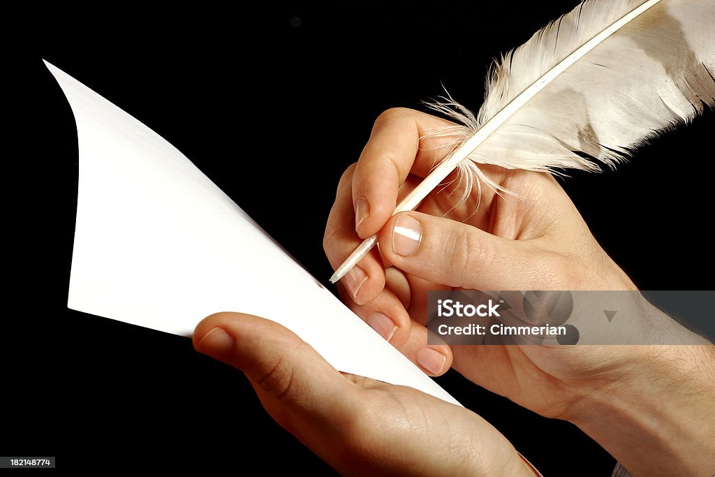 Author at work A hand writing with a feather pen. Black background. Space for copy Quill Pen Stock Photo