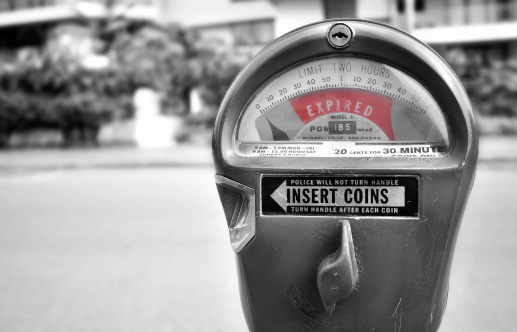 A b/w image of a parking meter with a red time expired notice.