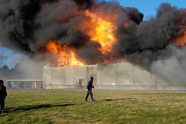 Photo of Warehouse on fire releasing think black smoke to the sky