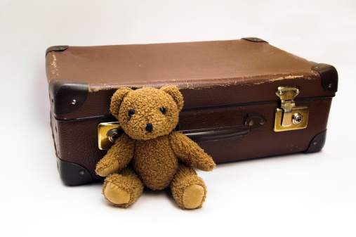 Old used suitcase with Teddy-bear isolated on white background.