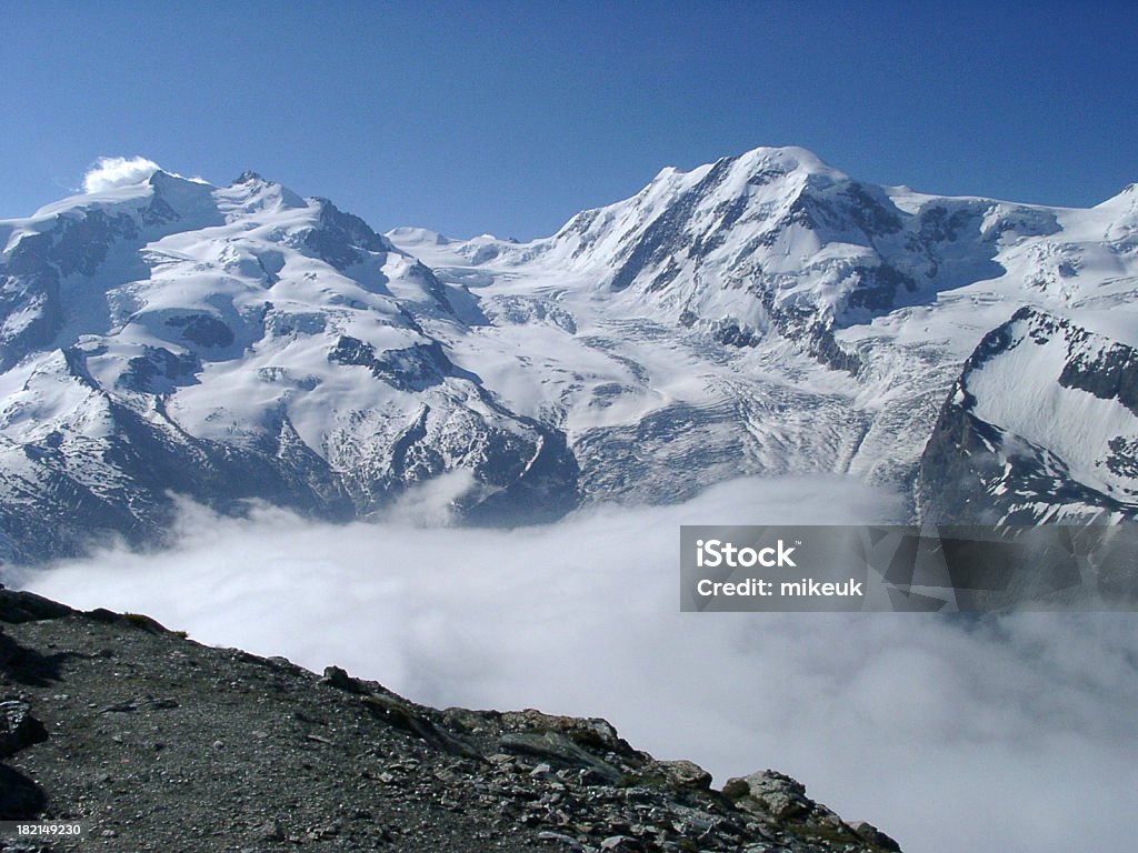 Alpine vista para a montanha, de manhã cedo, com nuvens no valley - Foto de stock de Adulto royalty-free