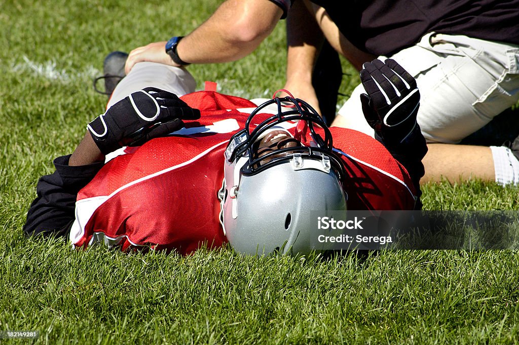 Pain in a game Injured American football player laying on a grass Physical Injury Stock Photo