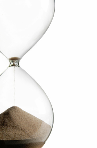 Beautiful old fashioned hourglass with turquoise coloured sand on white background: time concepts