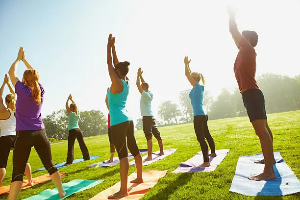 Young group of sportspeople taking a yoga class outdoors