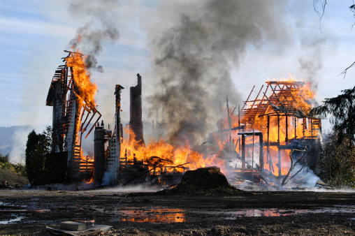 Old farm house completely consumed by fire is burnt to the ground.