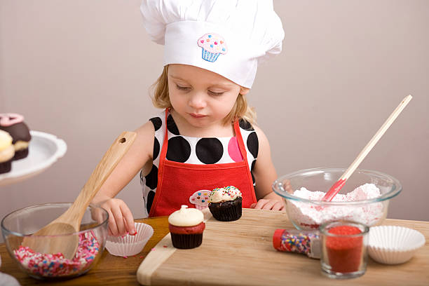 istock Cupcake Decorating by Little Girl in Chef's Hat and Apron 182149681