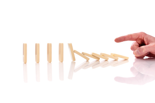 Domino effect, man's hand is pushing domino pieces, isolated on white background, copy space, horizontal.