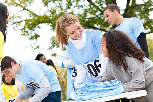 Teenager helping little girl sign up at charity event race Teenager helping little girl sign up at charity event race. walking for a cause stock pictures, royalty-free photos & images