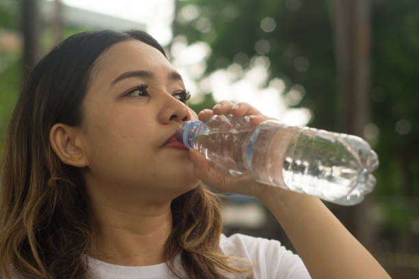 istock Asian Woman Drinking Water from Plastic Bottle at Public Park 1821516129