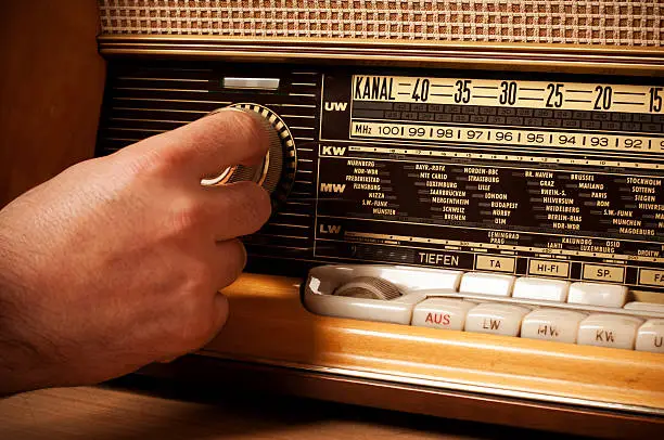 Photo of Vintage short wave radio with person's hand on the tuner