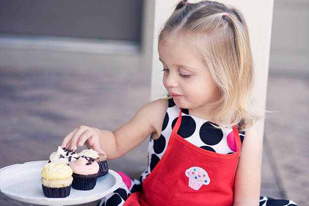 istock Little Girl Enjoying Cupcakes Outdoors on Patio 182152242