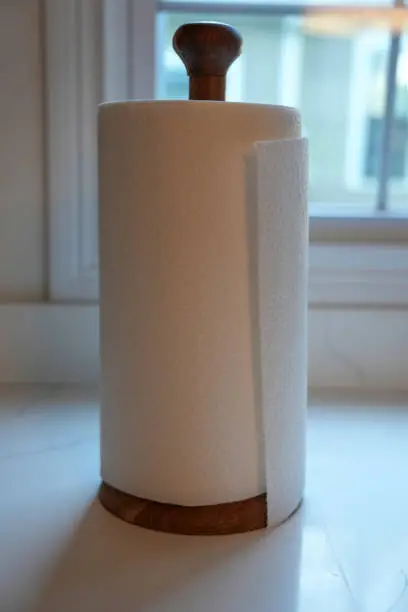 Wooden paper towel holder on kitchen countertop in front of window