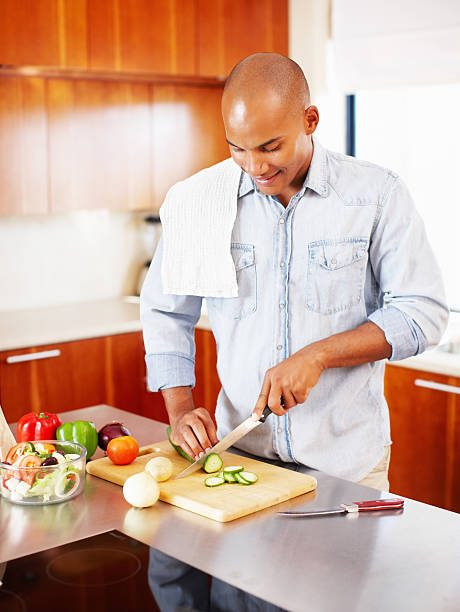 istock Young man chopping cucumber in kitchen 182154540
