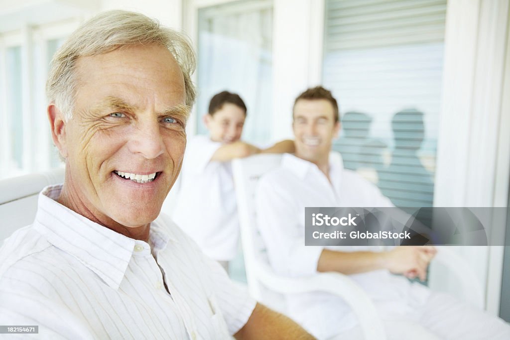 Hombre mayor sonriendo con su familia en el fondo - Foto de stock de 30-39 años libre de derechos