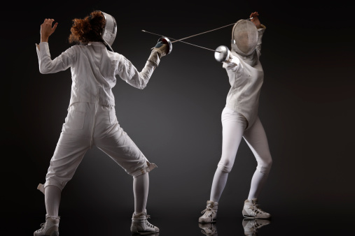 Fencing. Two fencers in action. Black background.SEE ALSO: