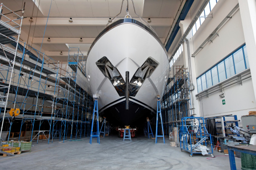Front view of a large luxury motor yacht in a ship building facility