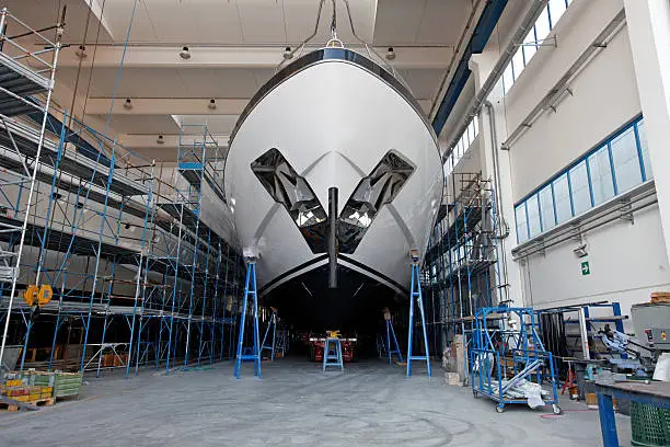 Front view of a large luxury motor yacht in a ship building facility