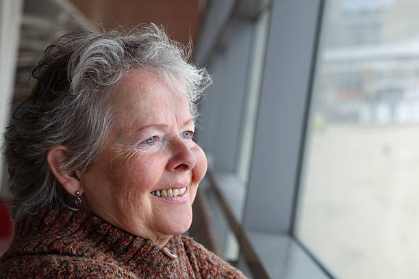 istock mature woman in knitted jacket looks through window 182155744