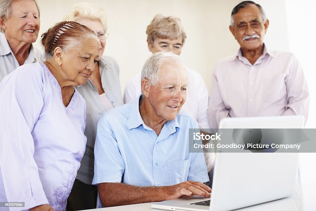 Homem sênior usando laptop com os amigos - Foto de stock de 70 anos royalty-free