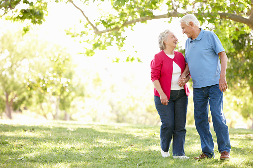 Senior couple in park holding hands smiling