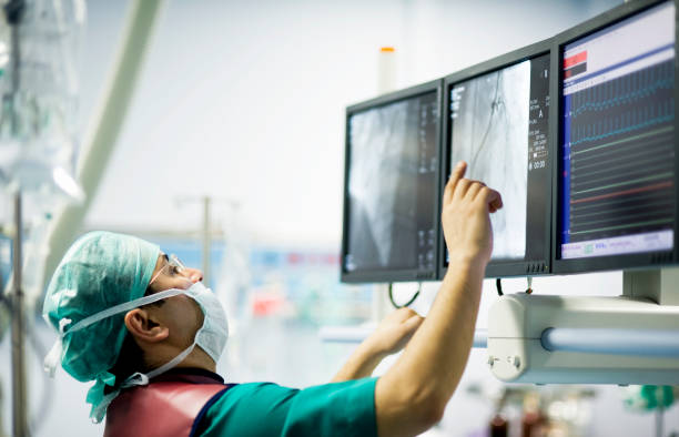 Cardiologist Doctor in the Operation Room "Cardiologist doctors are in a angio operation, one of the doctors following the LCD screens for the stent... ( real life )" operating room photos stock pictures, royalty-free photos & images