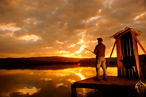 man at sunset in a lake fishing . hobby and individual sport.