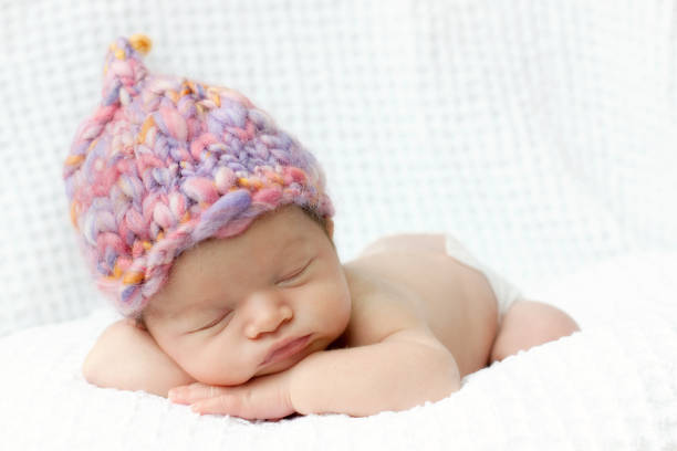 Newborn baby asleep with pink hand knit hat stock photo