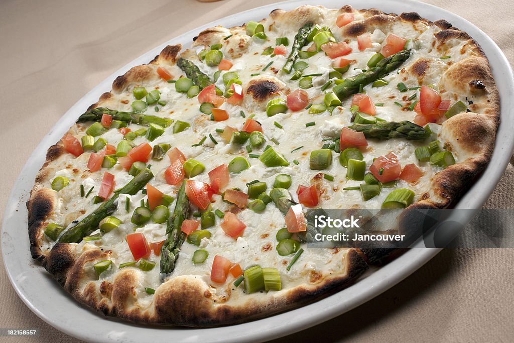 Asparagus and goat cheese pizza "Asparagus and goat cheese pizza, topped with mozzarella, chives and tomatoes" Appetizer Stock Photo