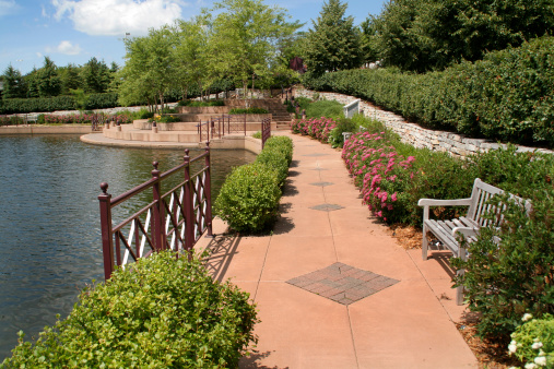 An urban park walking path with shrubs and landscaping, a city scene by a lake in Edina, Minneapolis, Minnesota, USA.