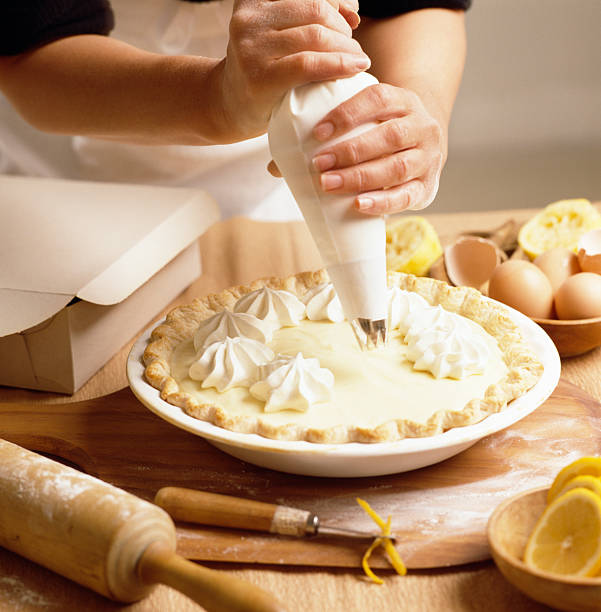 Piping cream onto Lemon meringue pie stock photo