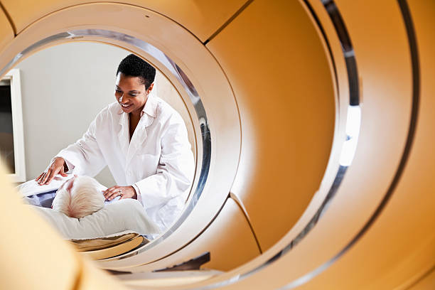 Radiologist preparing patient for PET-CT scanner View of radiologist or technician with senior male patient through an integrated PET-CT scanner. pet scan photos stock pictures, royalty-free photos & images