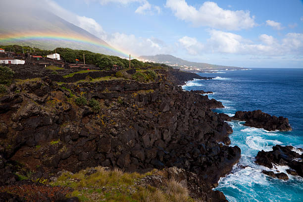Azorean landscape with lava cliffs and rainbow Rainbow on the coastline of PIco island, Azores, Portugal madalena stock pictures, royalty-free photos & images