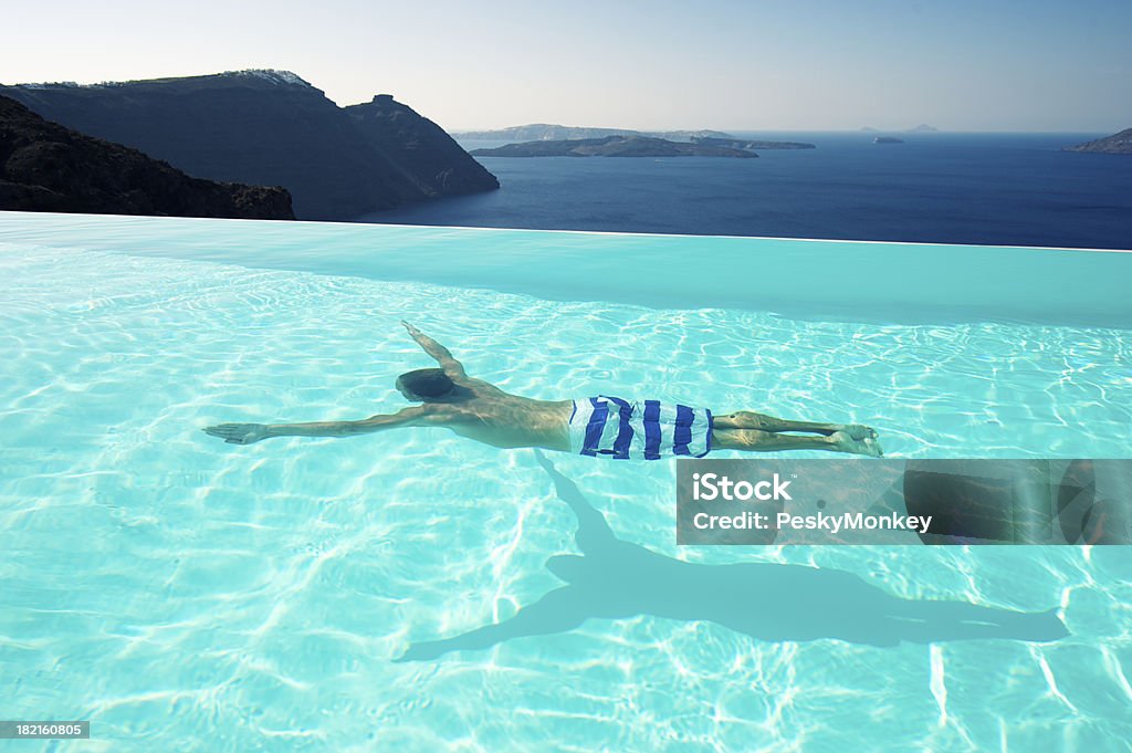 Man Swimming Underwater piscina de borde infinito de Escape de Santorini, Grecia - Foto de stock de Piscina libre de derechos