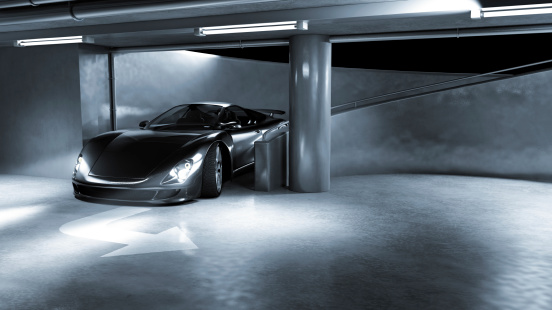 A black sports car driving down a ramp in an underground carpark. My own sports car design. Very high resolution 3D render.