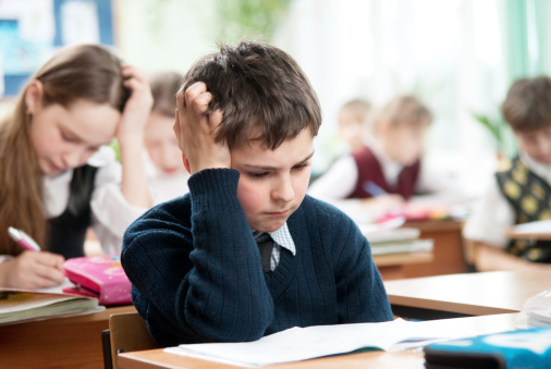 Schoolboy sitting at the classroom and working hardly