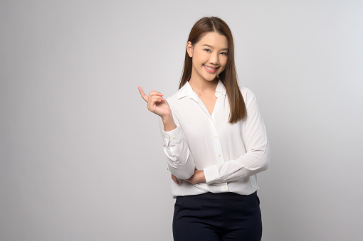 Attractive young woman , brunette, with a beaming smile, giving a thumb up gesture of approval and success