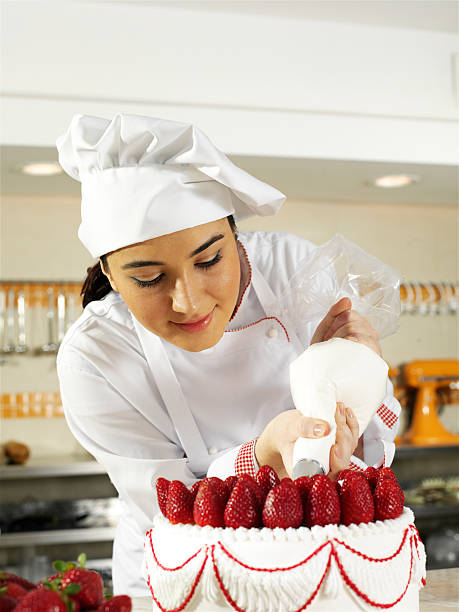 istock Female baker decorating a large cake with whole strawberries 182164261