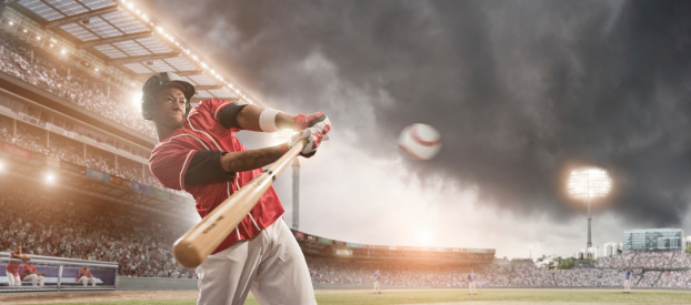 professional baseball player about to strike baseball in floodlight baseball stadium under stormy sky