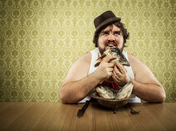 istock hungry fat man licking fish head soup at wood table 182165025