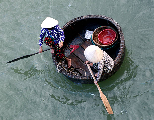 Basket Boat "Two anonymous women heading out to sea in a basket -- a fishing vessel native to Nha Trang, Viet Nam.  Most likely getting ready to check traps for shrimp, crabs, & lobsters.VIET NAM 2006 LIGHT BOX:" basket boat stock pictures, royalty-free photos & images