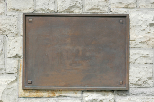 Placa conmemorativa de bronce en pared de piedra photo