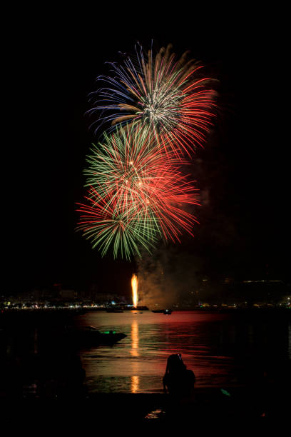 海辺の人々と街の常夜灯の背景とカラフルな花火のお祝い。 - fire firework display new year ストックフォトと画像