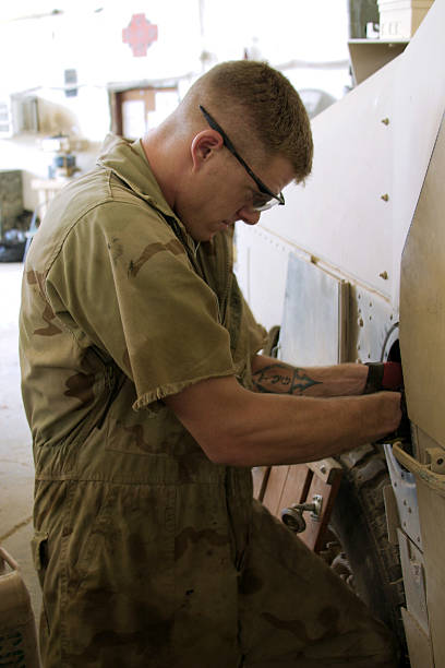 Military personnel performing maintenance on a vehicle stock photo